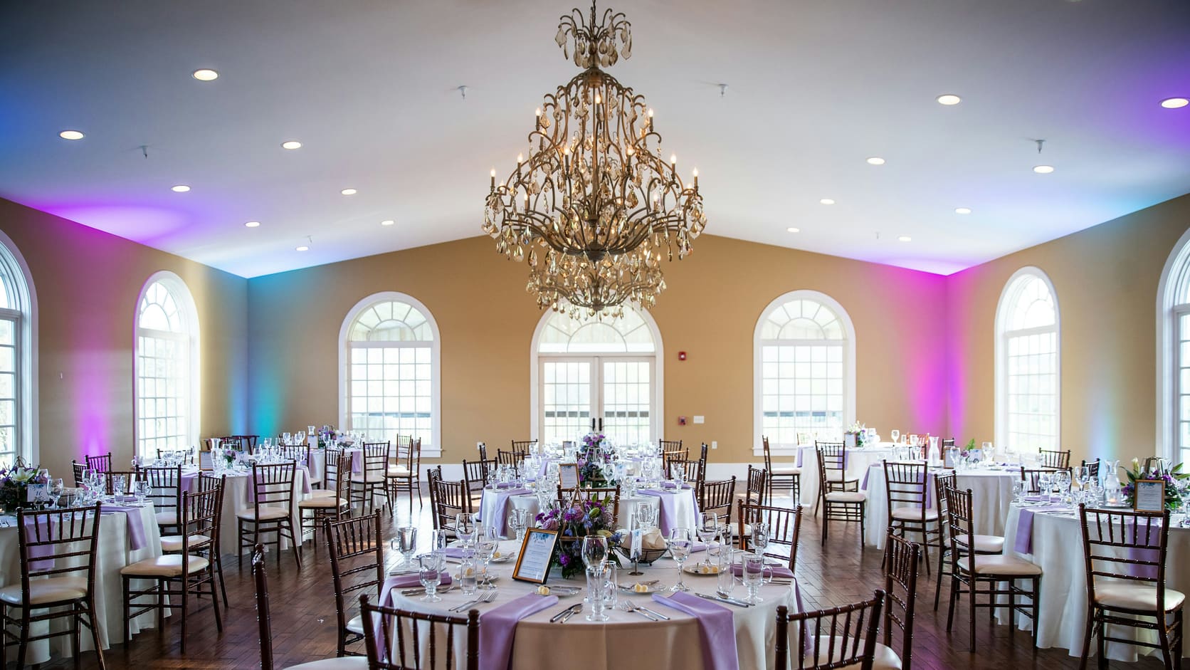Illustrative banquet hall with a crystal chandelier and elegantly set round tables